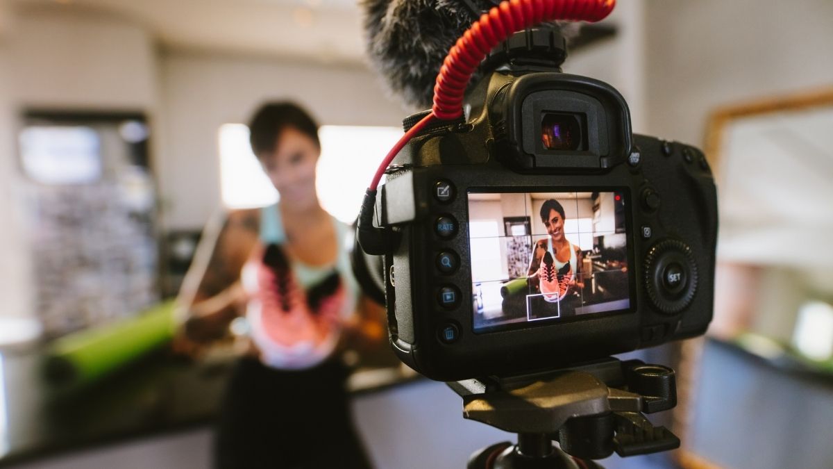 woman filming trainer unboxing video on DSLR camera