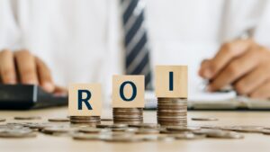 three letter blocks spelling out ROI on top of piles of coins